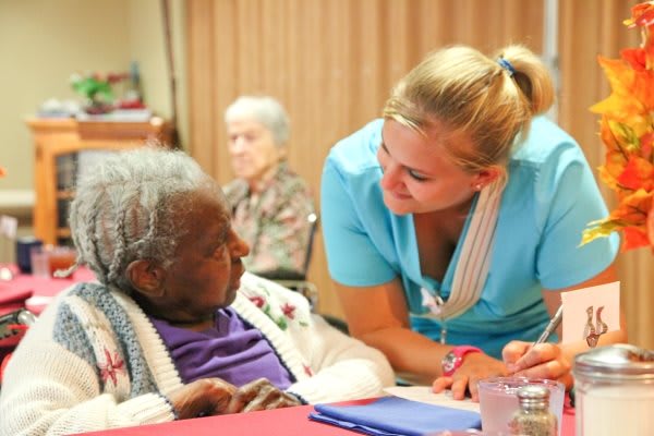 A nurse attentively interacts with an elderly person, providing care and support.