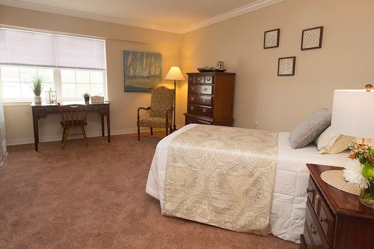 A cozy bedroom with a neatly made bed, desk, and warm lighting.