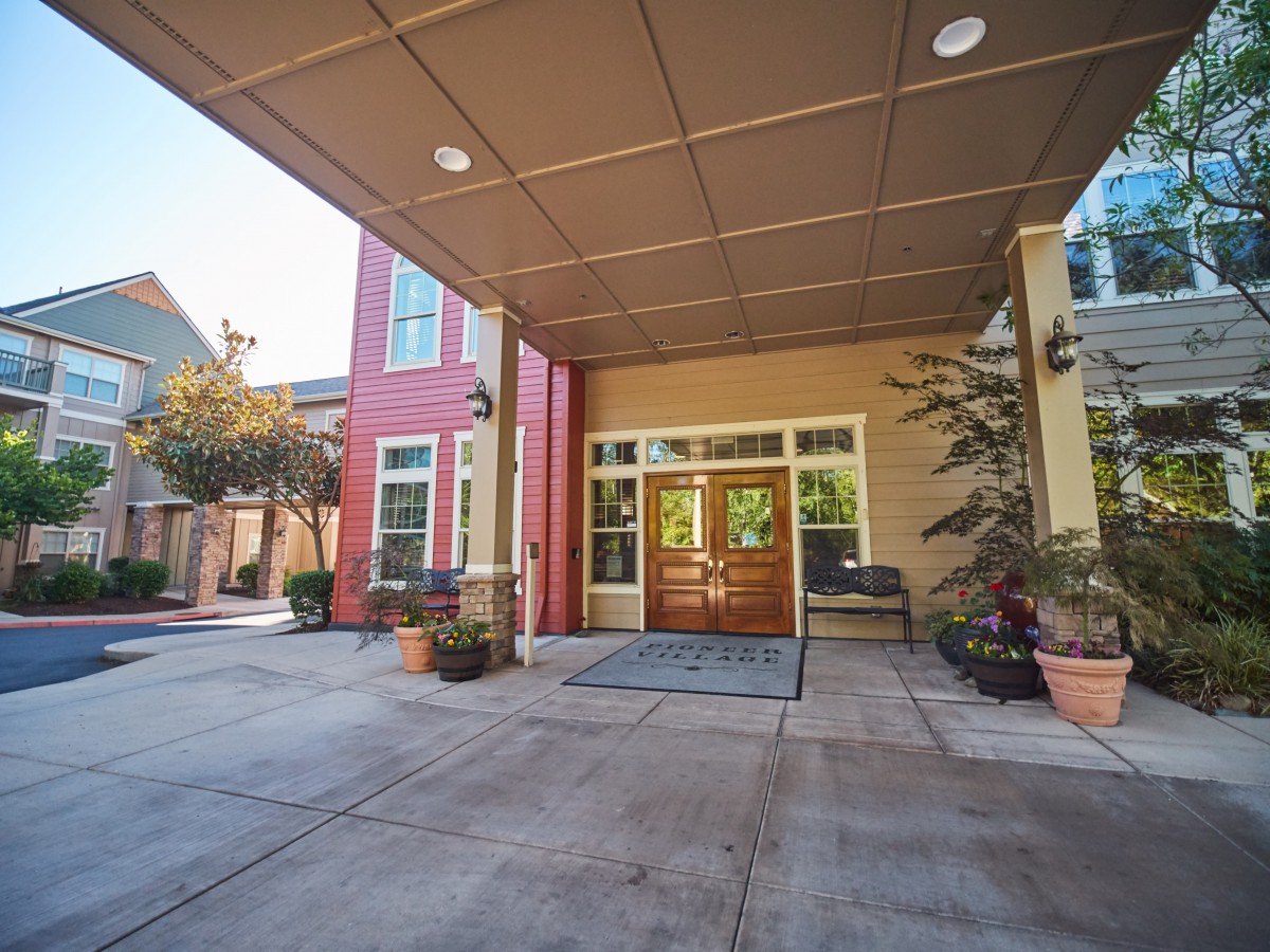 A covered entrance to a building with surrounding plants and a welcoming atmosphere.