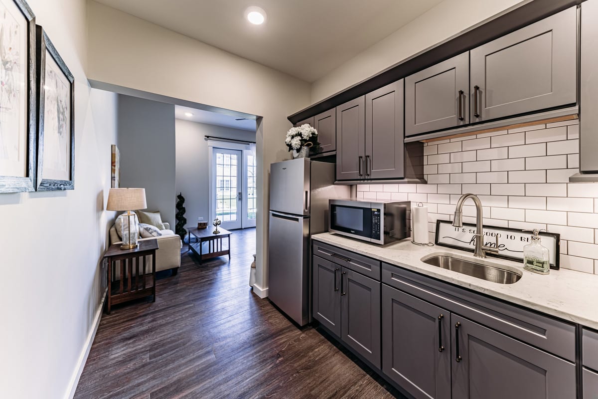 Modern kitchen with dark cabinets and a view into the living area.
