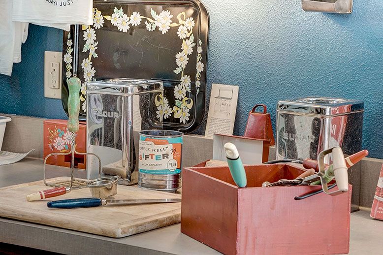 A collection of vintage kitchenware items displayed on a countertop, featuring various utensils and decorative pieces.