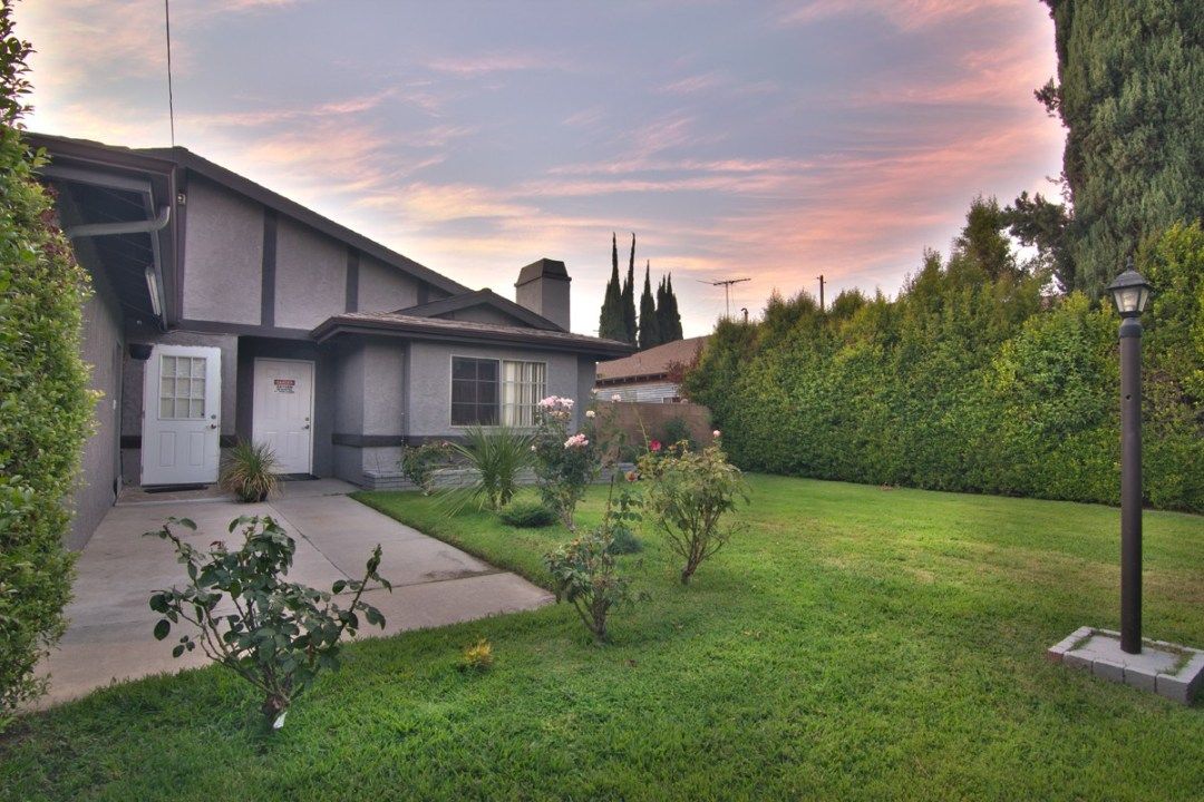 A beautiful yard with a well-maintained lawn and garden, showcasing a house at sunset.
