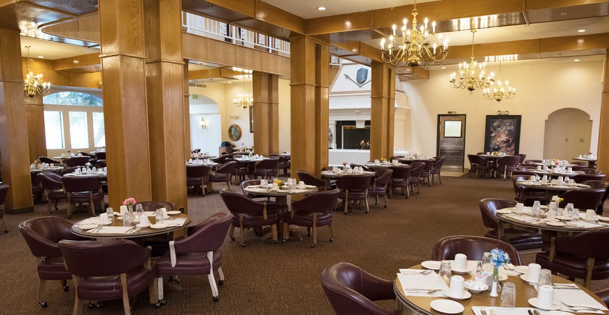 An elegant restaurant dining area with neatly arranged tables and chairs, featuring a chandelier.