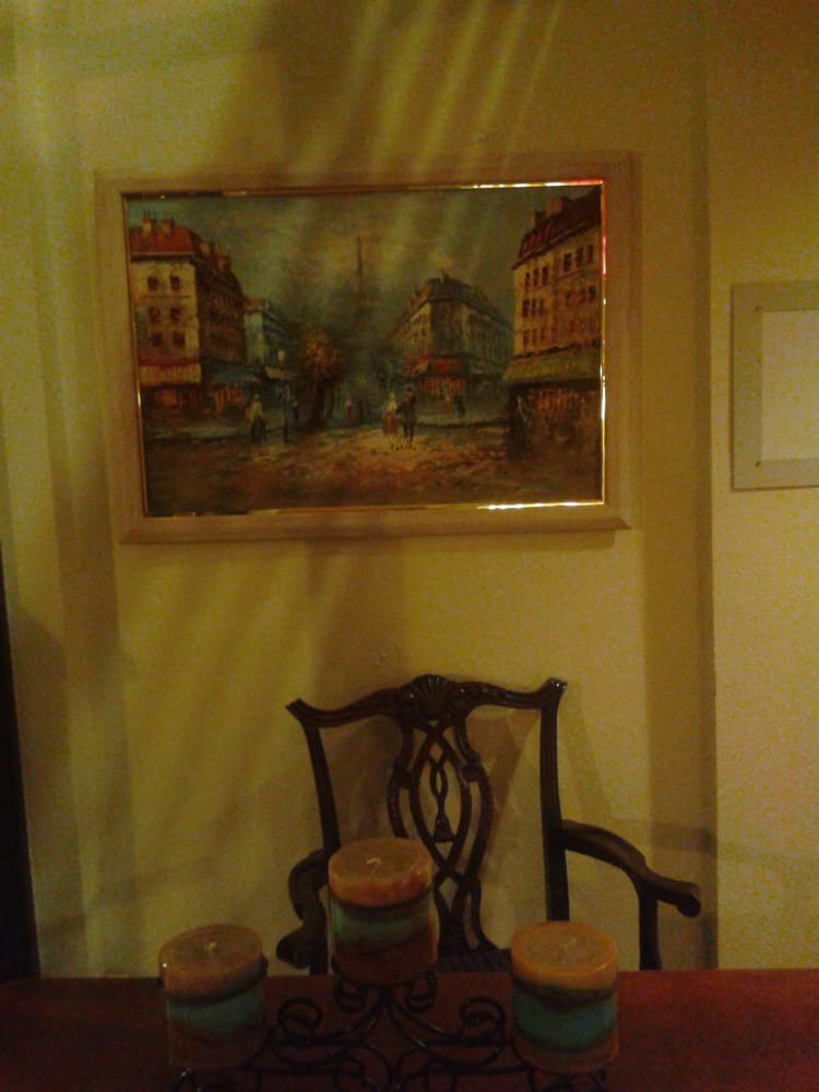 A room interior featuring a framed painting above an ornate chair.