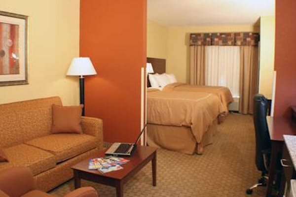 A cozy hotel room with a double bed, sofa, and warm lighting.