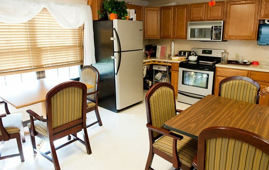 A cozy kitchen with wooden cabinets, a refrigerator, and a dining table with chairs.