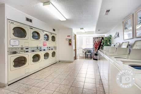 A clean and spacious laundromat featuring rows of washing machines, dryers, and a vending machine.