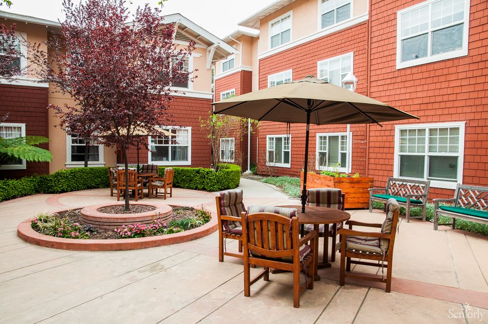 A cozy courtyard with outdoor seating and umbrellas in an apartment complex.