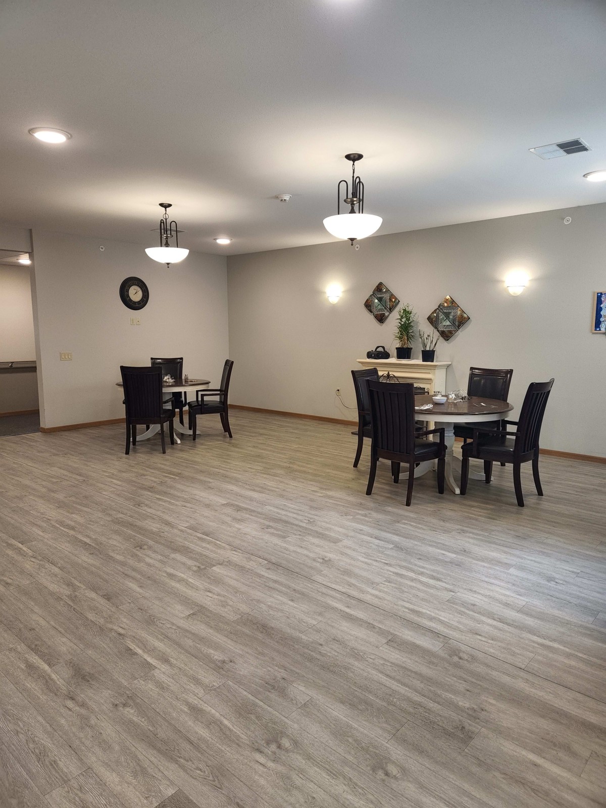 A spacious modern dining area with tables and chairs, featuring wooden flooring and stylish lighting.