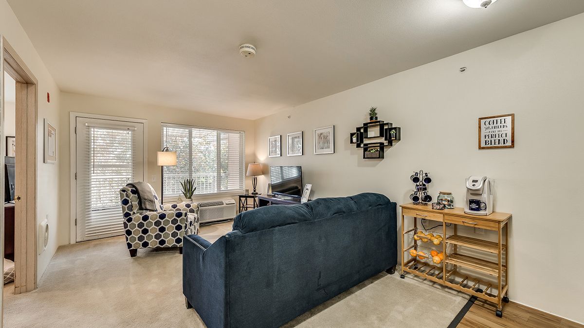 A cozy living room with a blue sofa, patterned armchair, and decorative artwork on the walls.