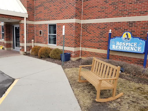 An outdoor view of a residential building featuring a wooden bench and a sign.