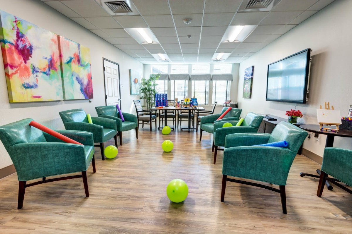 A colorful office lobby with chairs arranged in a circle and balloons scattered around.