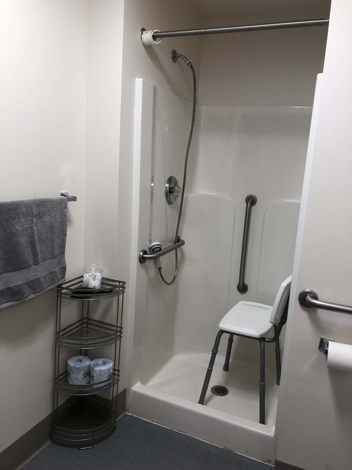 A bathroom featuring an accessible shower with a chair and grab bars for safety.