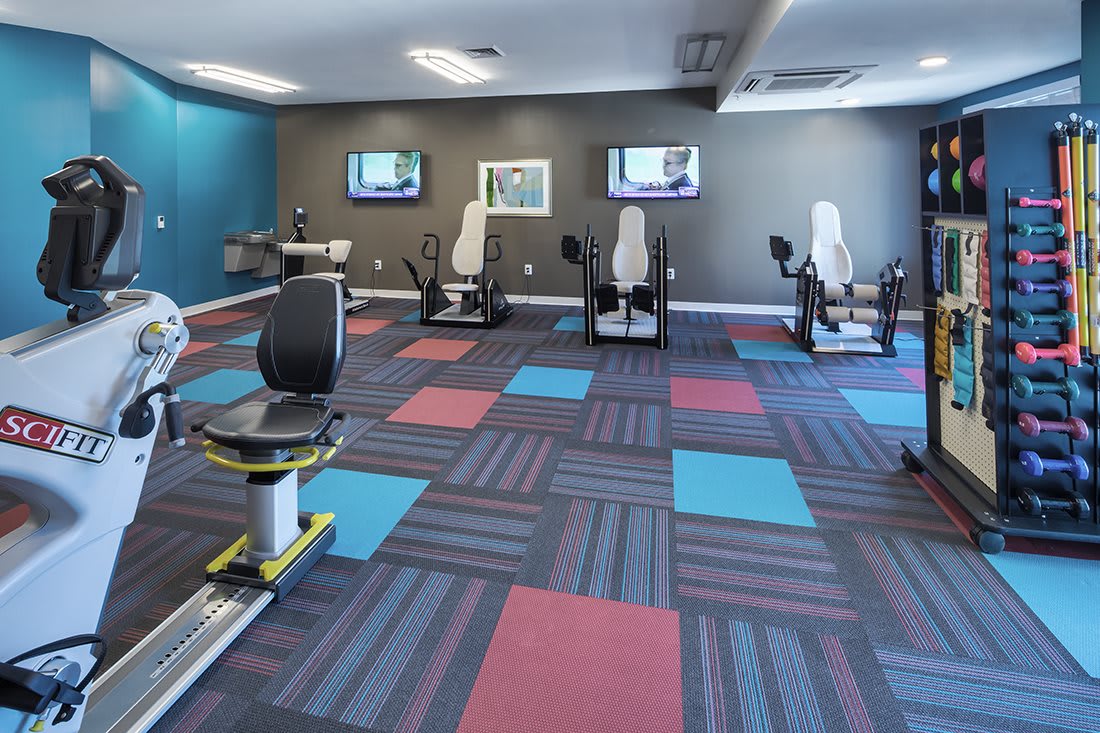 A brightly colored gym with modern exercise equipment and patterned flooring.