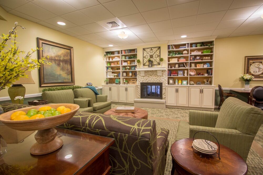 A cozy living room with a fireplace and neatly arranged shelves, featuring comfortable seating and warm decor.