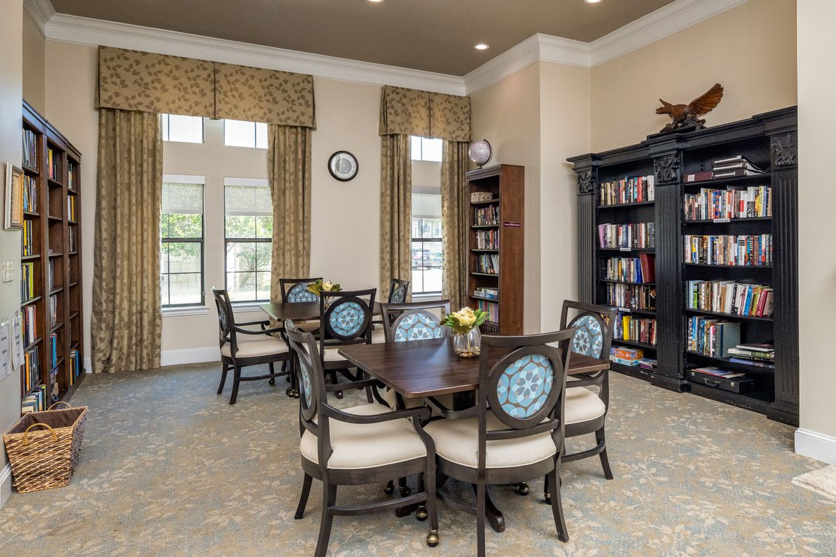 A cozy library room with a large table and bookshelves.