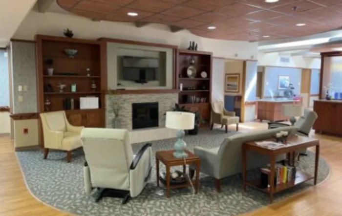 A cozy living room with comfortable seating, a fireplace, and bookshelves.