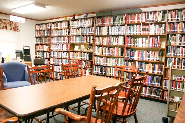 A cozy library corner with bookshelves filled with books, accompanied by a wooden table and chairs.