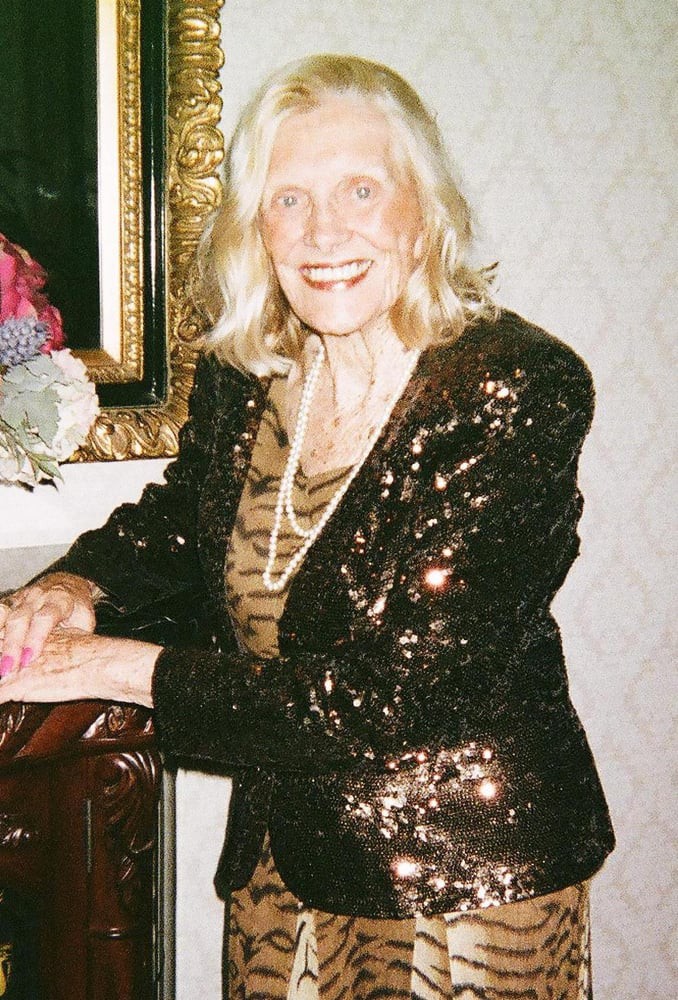 An elegant woman in a sequin jacket smiling indoors.