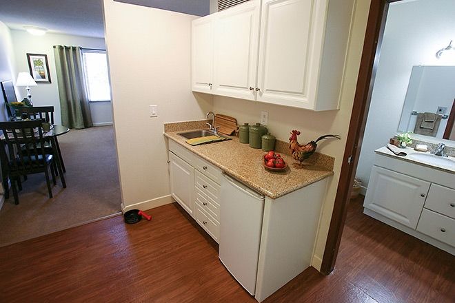 A small kitchenette with white cabinets and a countertop featuring decorative items.