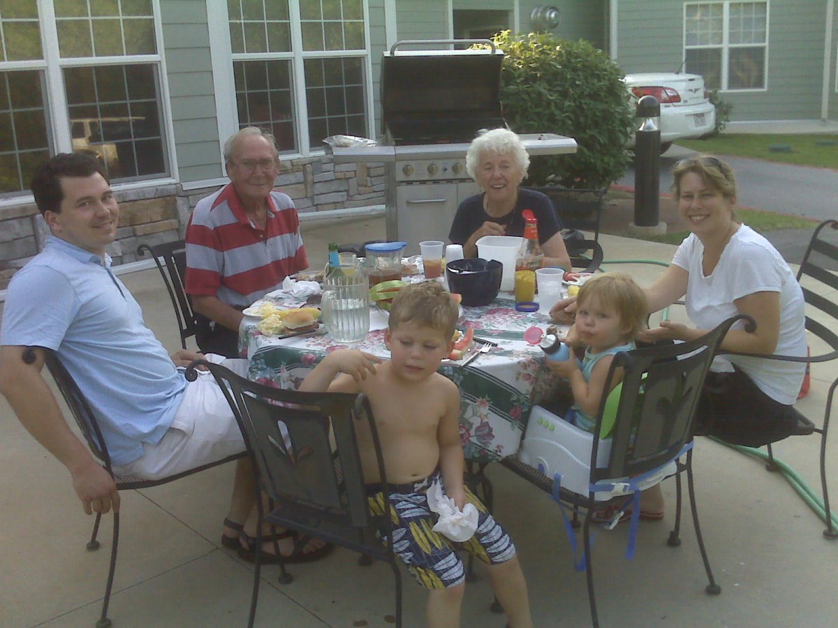 A family enjoying a meal together outdoors on a sunny day.