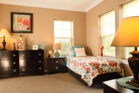 A cozy bedroom with a single bed, colorful bedding, and matching decor.