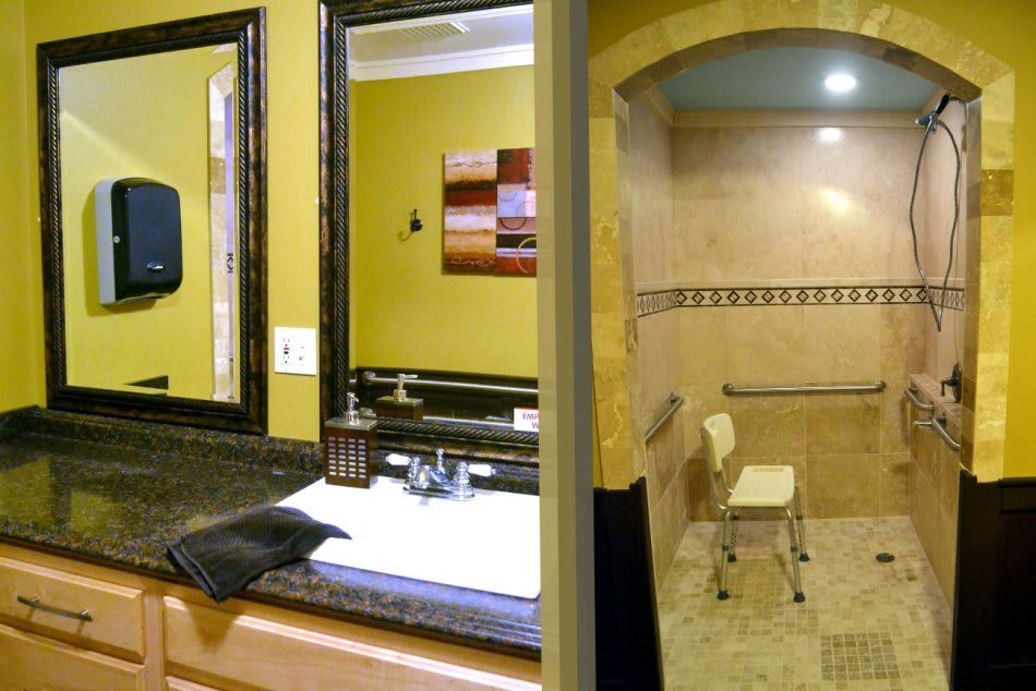 A well-designed bathroom with a large mirror, sink, and accessible shower area.