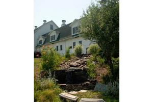 A charming house set atop a landscaped garden with stone features.