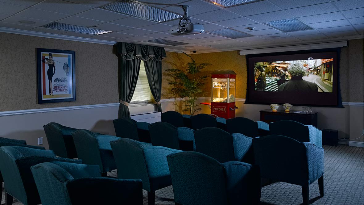 A cozy theater room with rows of seating and a popcorn machine.