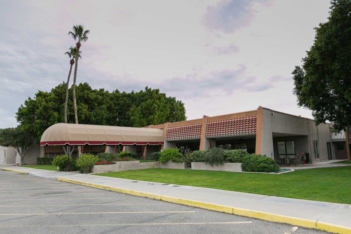 A modern office building surrounded by palm trees and greenery.