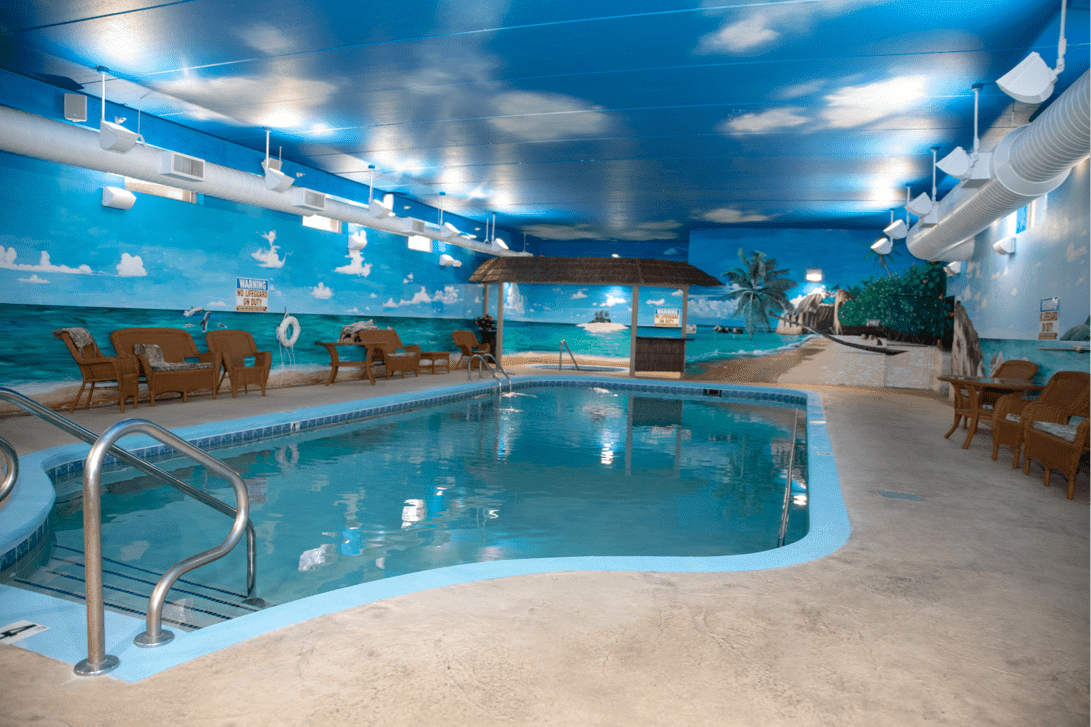 An indoor swimming pool with a tropical-themed decor and artificial lighting.