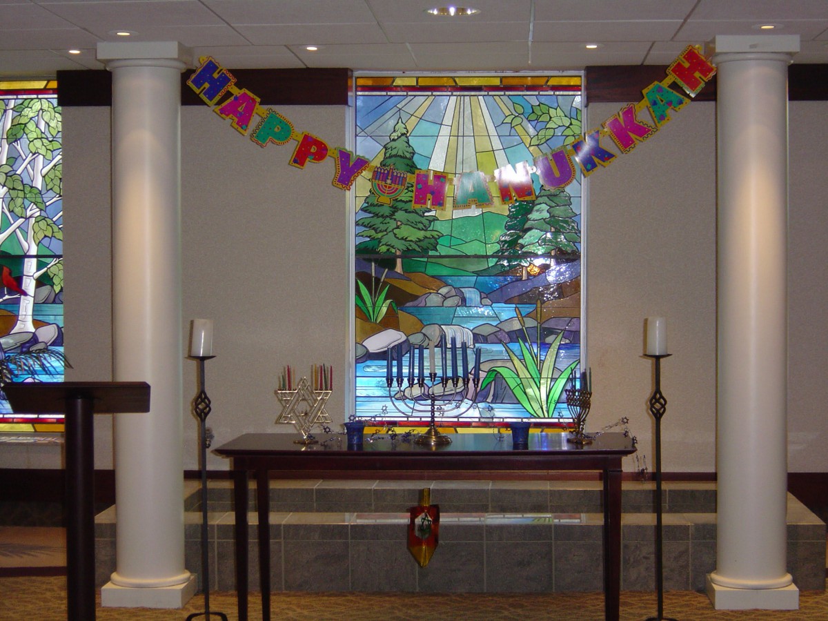 A decorated room with a 'Happy Birthday' banner, stained glass window, menorah, and candles.