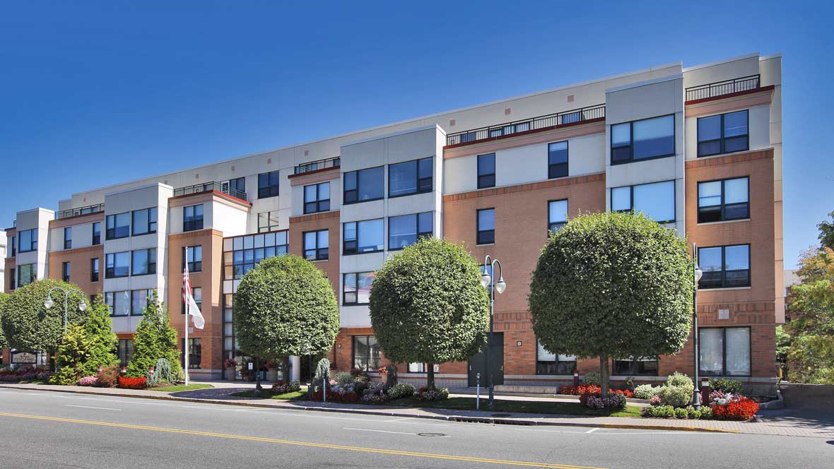 A modern hotel building with neatly trimmed trees along the street.