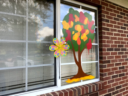 A vibrant and colorful window decoration featuring a fall-themed tree and floral design.