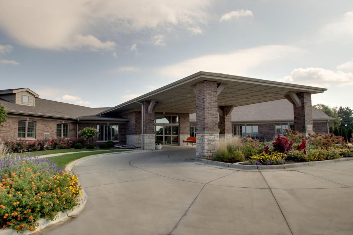 A well-maintained building entrance with a circular driveway and landscaped surroundings.