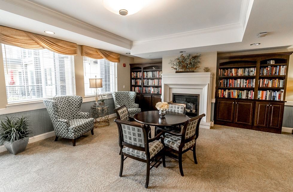 A cozy library interior with bookshelves, a fireplace, and seating area.