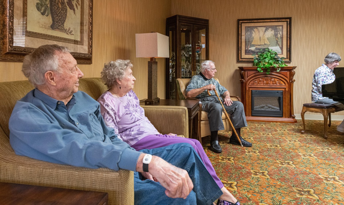 Elderly residents gather in the common area of a nursing home for a social moment.