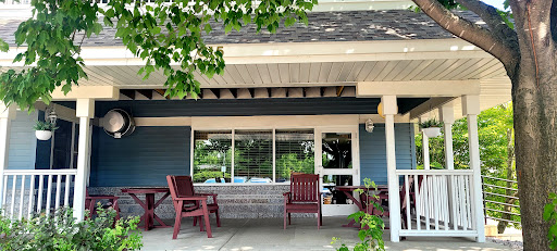 A cozy outdoor seating area in front of a building, surrounded by greenery.