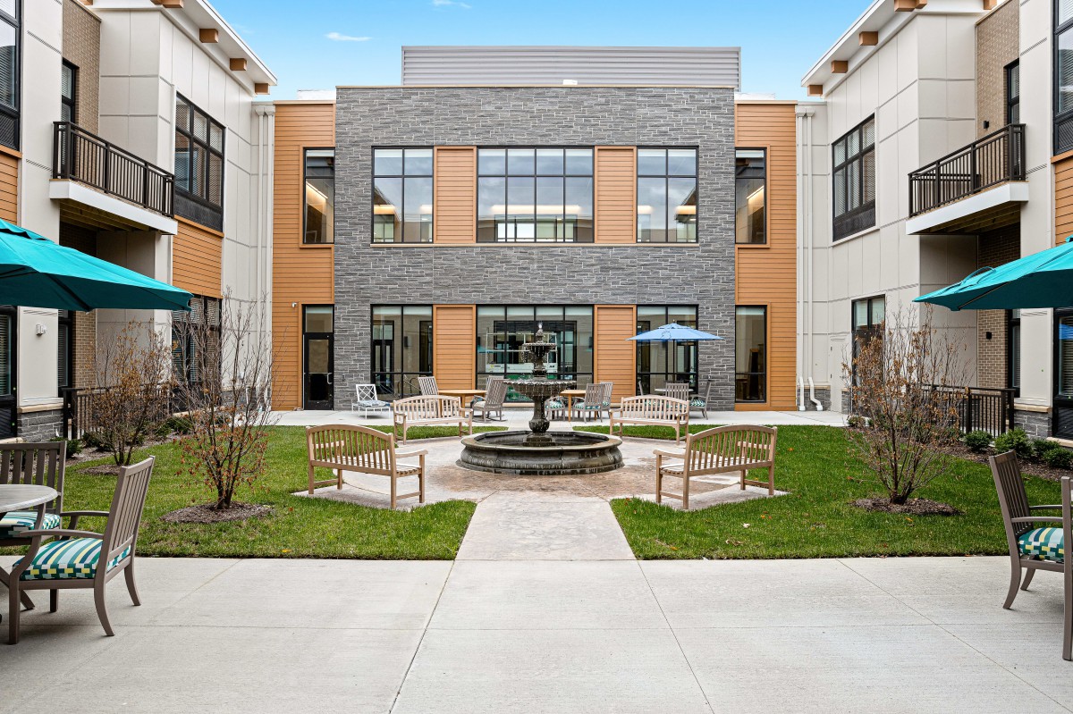 A modern building with a courtyard featuring a central fountain and seating area.