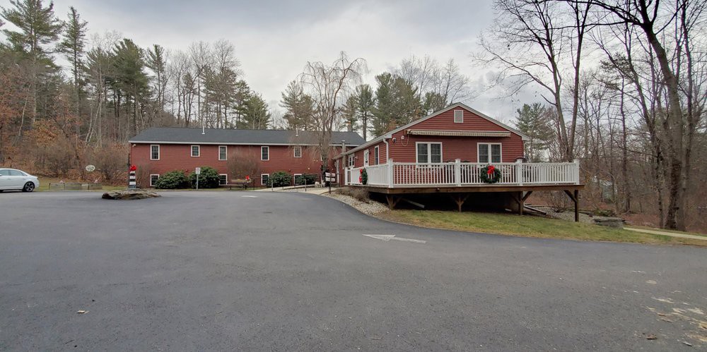 A red brick building complex with an adjacent road and trees under an overcast sky.