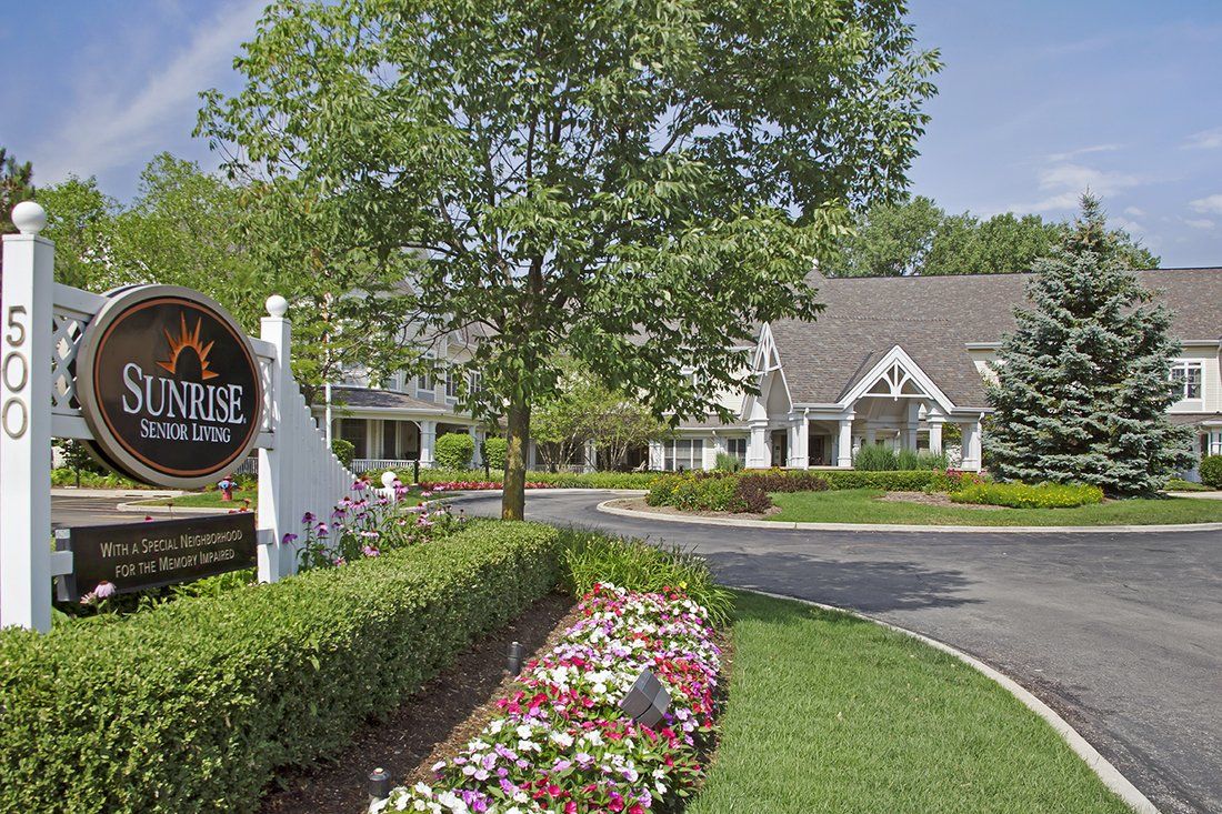 A scenic view of a building entrance with colorful flowers and lush greenery.