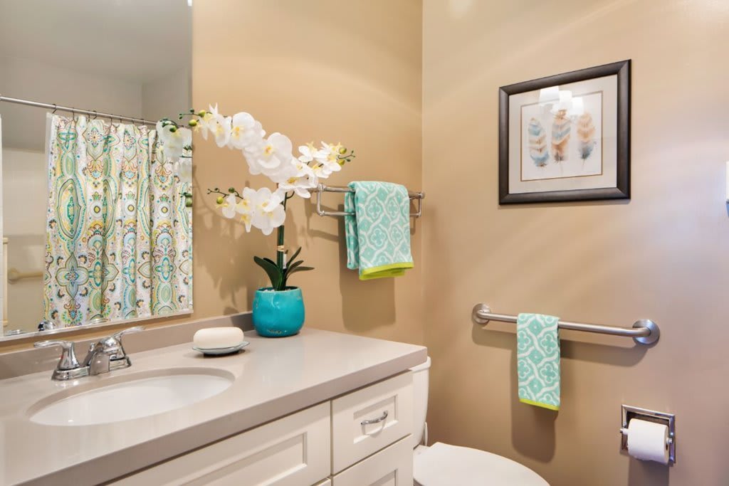 A neatly decorated bathroom with a vase of flowers and colorful towels.