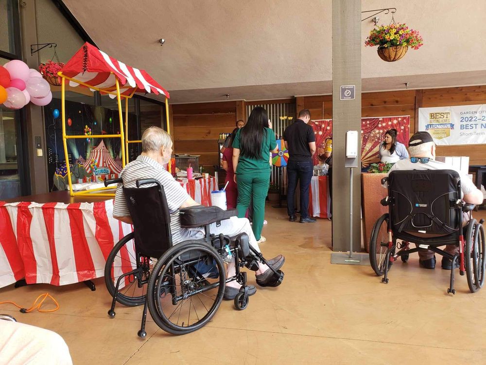 A community event at a healthcare facility featuring caregivers and elderly individuals in wheelchairs.