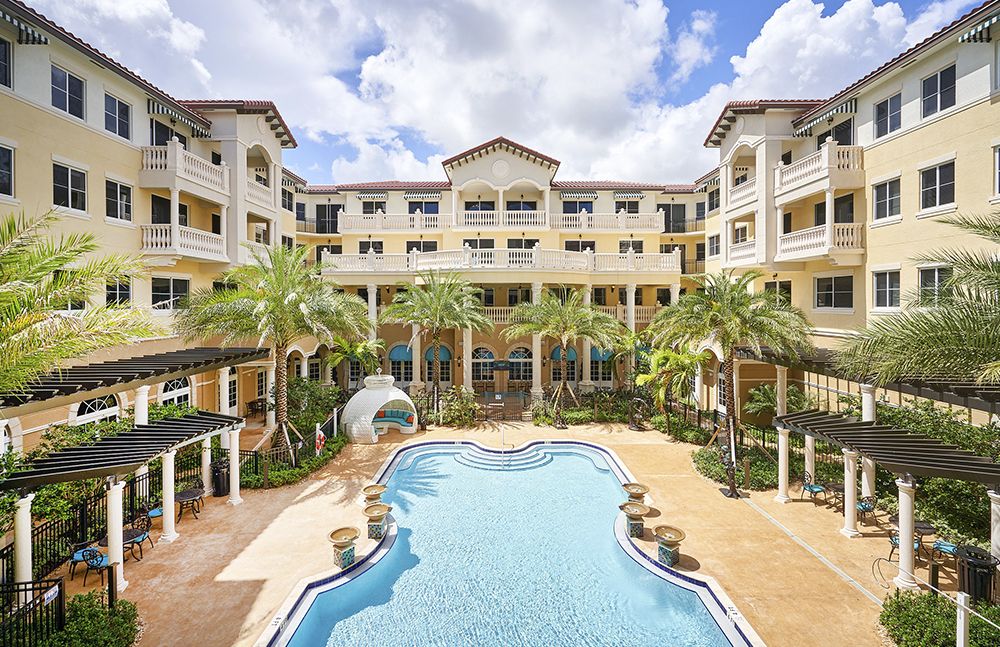 A luxurious resort with a central swimming pool surrounded by palm trees and elegant architecture.