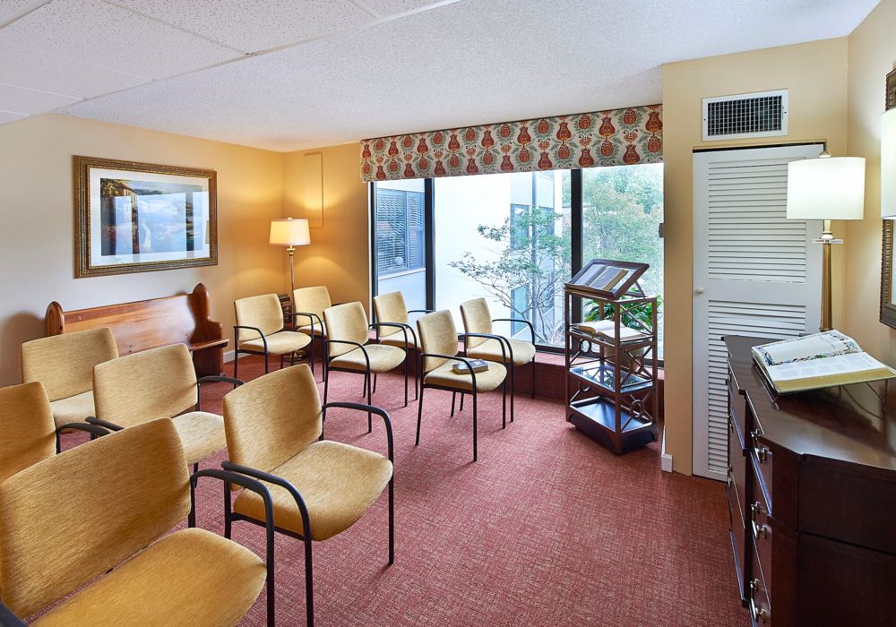A cozy waiting room with chairs arranged neatly, featuring large windows and a warm, inviting atmosphere.
