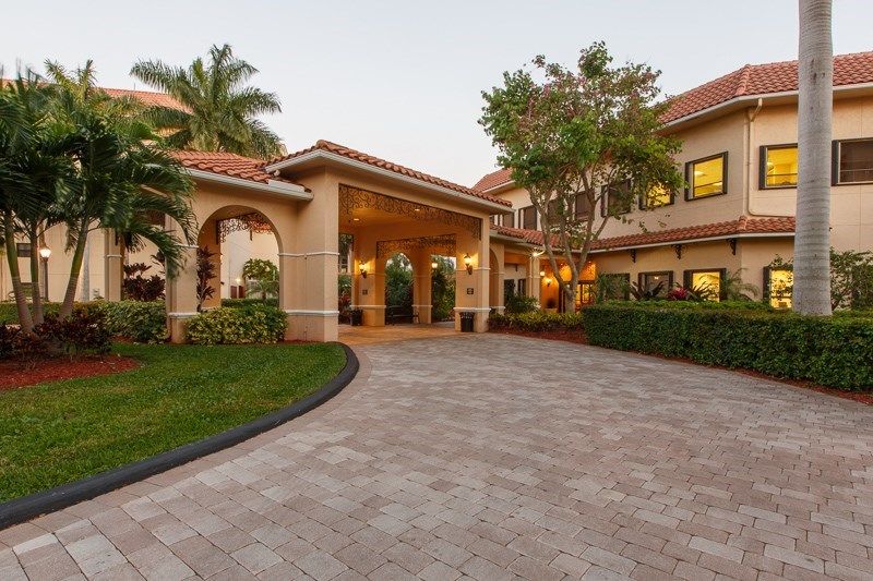 A picturesque driveway leading to a beautifully designed residential building surrounded by manicured landscaping.