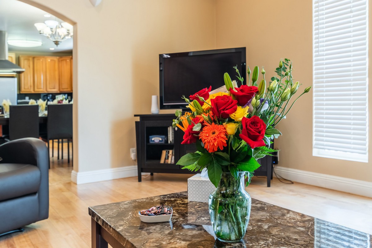 A cozy living room with a bouquet of colorful flowers on the coffee table and a television in the background.