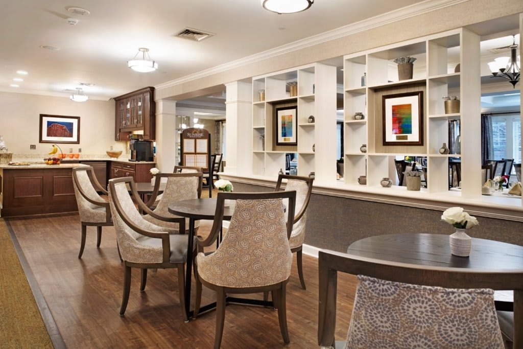 A cozy dining area featuring elegant tables and chairs, with shelves displaying artwork and decorative items.