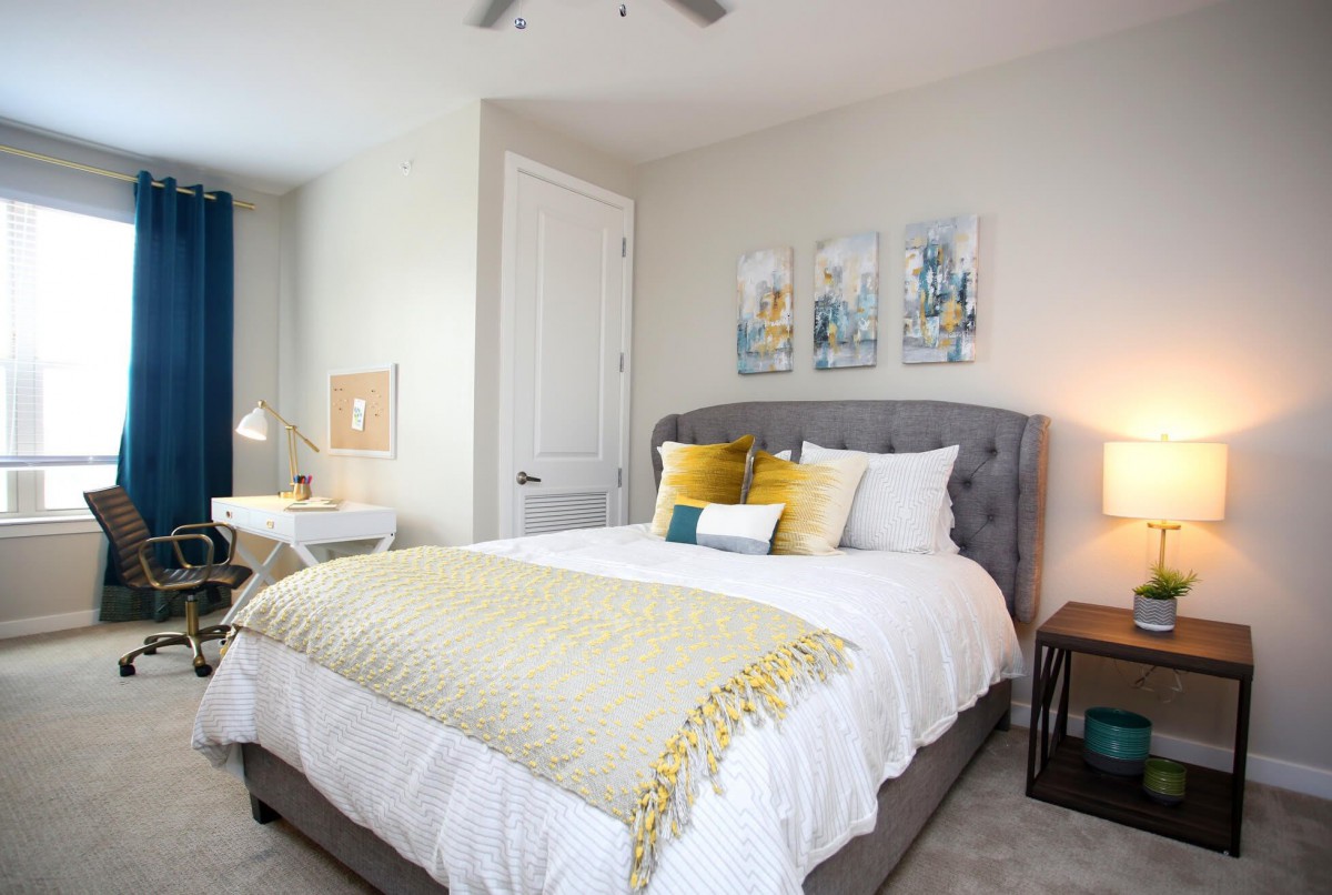 A modern bedroom with a well-decorated bed, featuring colorful pillows and a cozy blanket, complemented by stylish artwork on the wall.