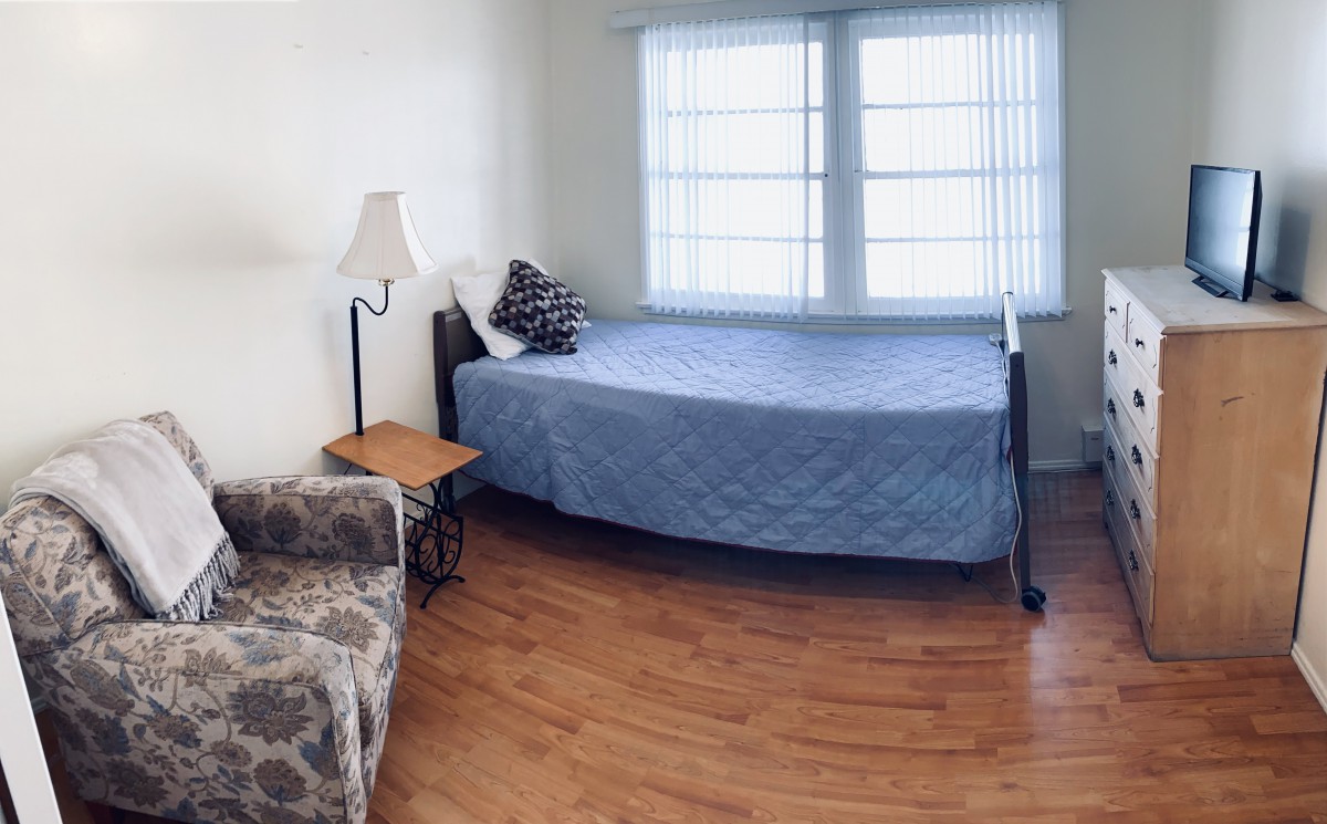 A cozy bedroom with a daybed, lamp, and window providing natural light.